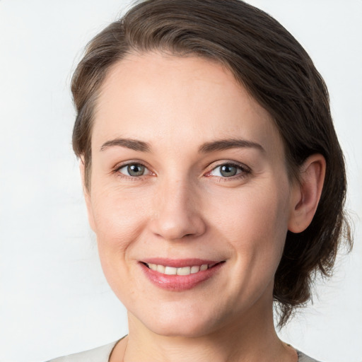 Joyful white young-adult female with medium  brown hair and grey eyes