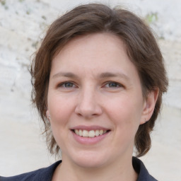 Joyful white young-adult female with medium  brown hair and grey eyes