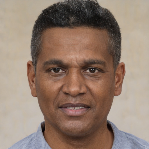 Joyful black adult male with short  black hair and brown eyes