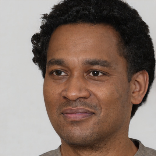Joyful black adult male with short  black hair and brown eyes