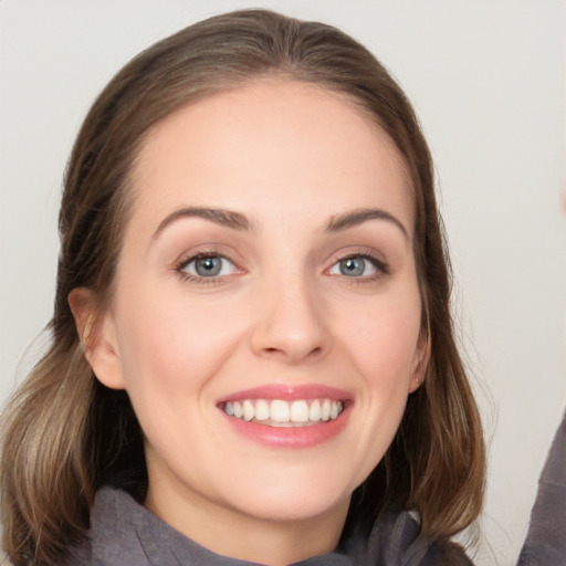 Joyful white young-adult female with long  brown hair and blue eyes