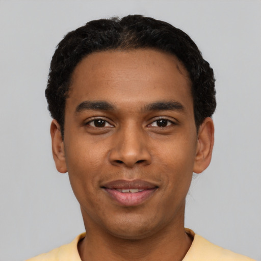 Joyful black young-adult male with short  black hair and brown eyes
