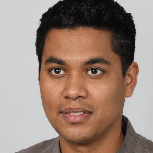 Joyful black young-adult male with short  black hair and brown eyes