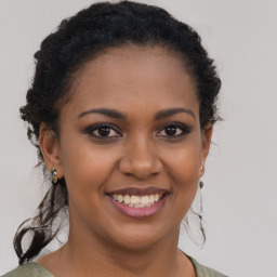 Joyful black young-adult female with long  brown hair and brown eyes