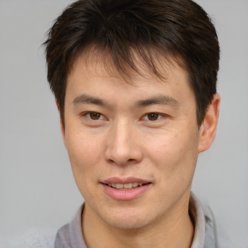 Joyful asian young-adult male with short  brown hair and brown eyes