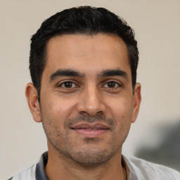 Joyful latino young-adult male with short  black hair and brown eyes