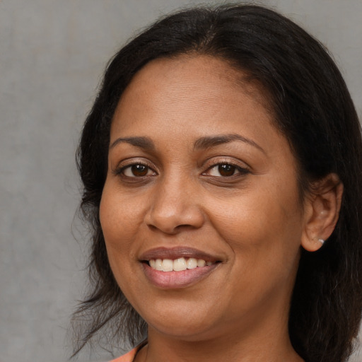 Joyful latino adult female with medium  brown hair and brown eyes