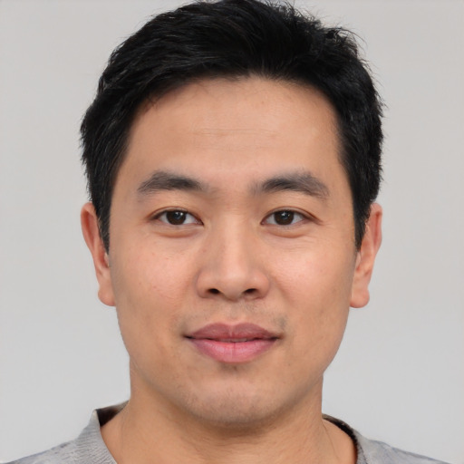 Joyful asian young-adult male with short  black hair and brown eyes