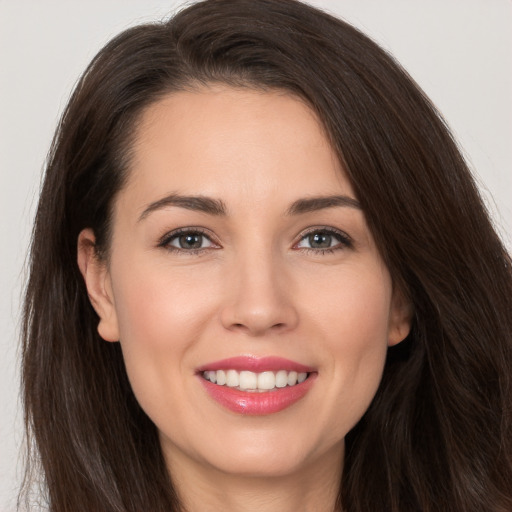 Joyful white young-adult female with long  brown hair and brown eyes