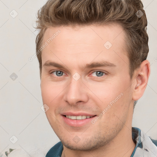 Joyful white young-adult male with short  brown hair and grey eyes