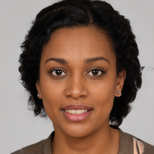 Joyful black young-adult female with long  black hair and brown eyes