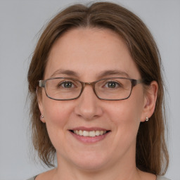 Joyful white adult female with medium  brown hair and blue eyes