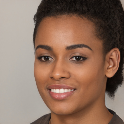 Joyful black young-adult female with short  brown hair and brown eyes