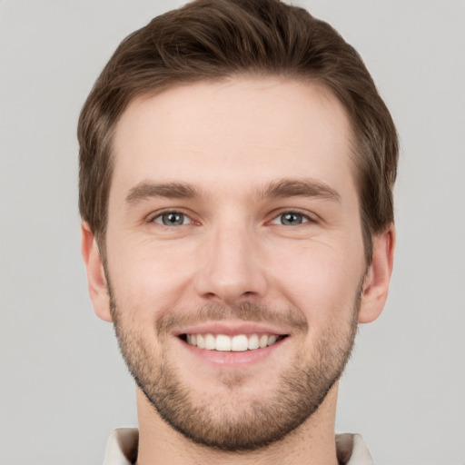 Joyful white young-adult male with short  brown hair and grey eyes