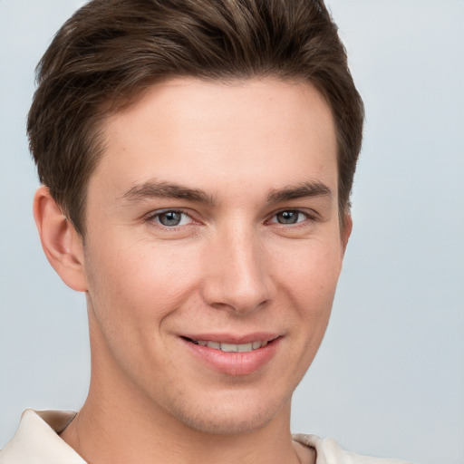 Joyful white young-adult male with short  brown hair and grey eyes