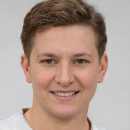 Joyful white young-adult male with short  brown hair and grey eyes