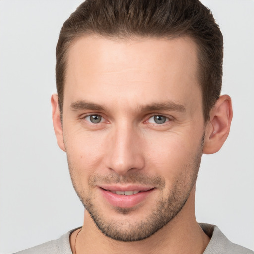 Joyful white young-adult male with short  brown hair and grey eyes