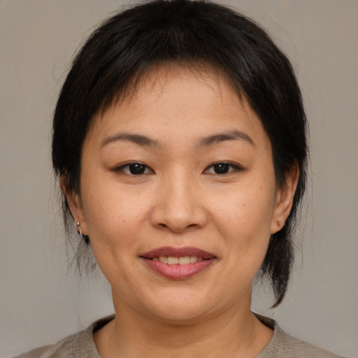 Joyful asian young-adult female with medium  brown hair and brown eyes