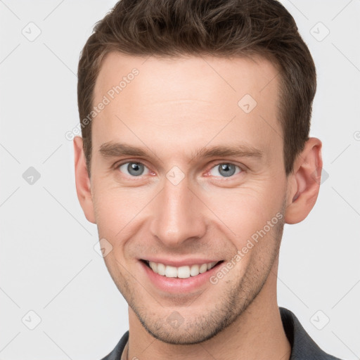 Joyful white young-adult male with short  brown hair and grey eyes