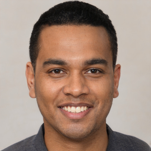 Joyful latino young-adult male with short  black hair and brown eyes