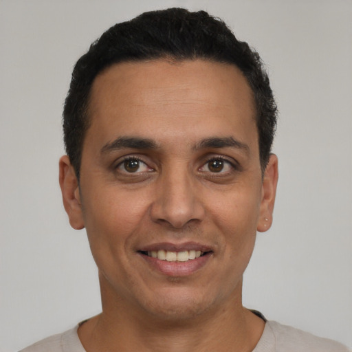 Joyful latino young-adult male with short  black hair and brown eyes