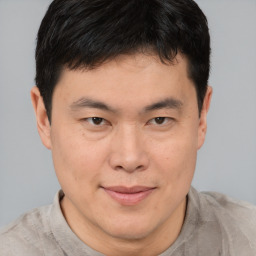 Joyful asian young-adult male with short  brown hair and brown eyes