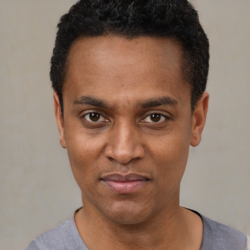 Joyful black young-adult male with short  black hair and brown eyes
