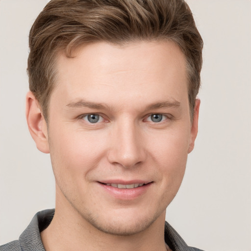 Joyful white young-adult male with short  brown hair and grey eyes