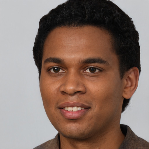 Joyful black young-adult male with short  black hair and brown eyes