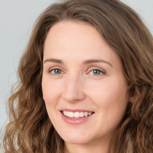 Joyful white young-adult female with long  brown hair and green eyes