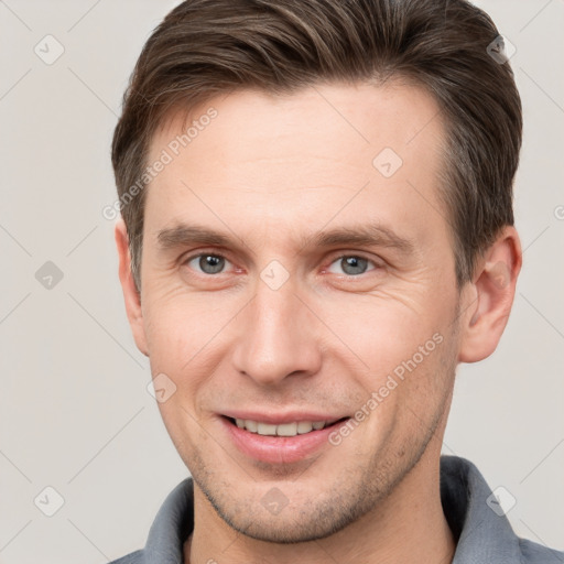 Joyful white young-adult male with short  brown hair and grey eyes