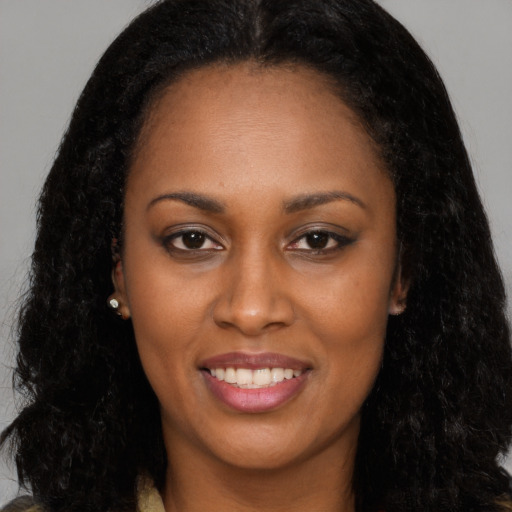 Joyful black young-adult female with long  black hair and brown eyes