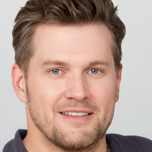 Joyful white young-adult male with short  brown hair and grey eyes