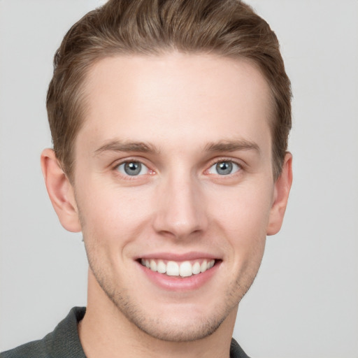 Joyful white young-adult male with short  brown hair and grey eyes