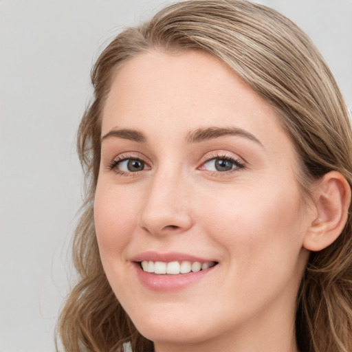 Joyful white young-adult female with long  brown hair and blue eyes