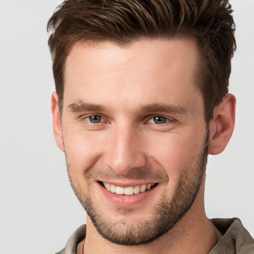 Joyful white young-adult male with short  brown hair and grey eyes