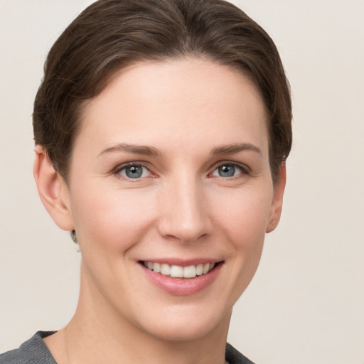 Joyful white young-adult female with short  brown hair and grey eyes