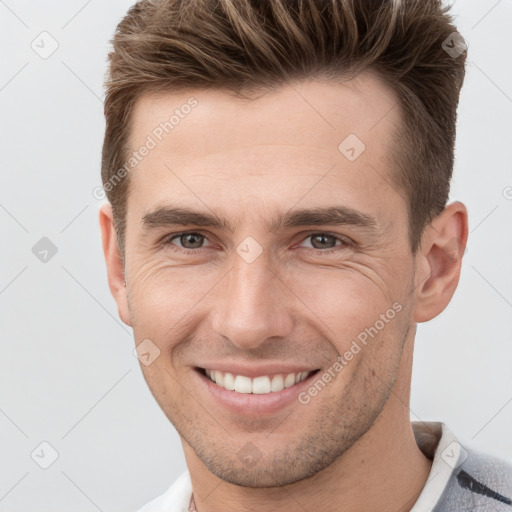 Joyful white young-adult male with short  brown hair and grey eyes