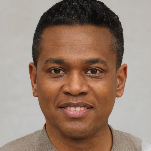 Joyful black young-adult male with short  black hair and brown eyes