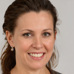 Joyful white adult female with long  brown hair and grey eyes