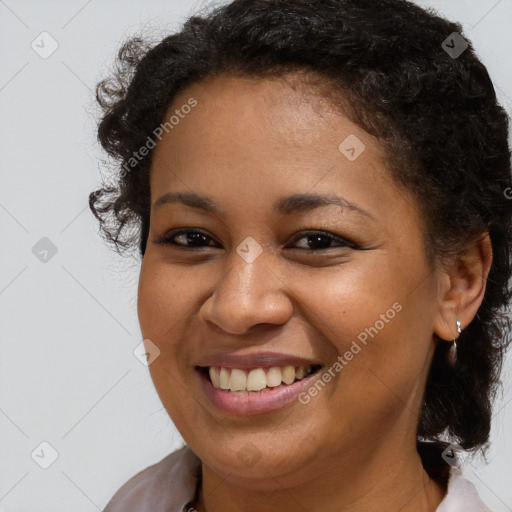 Joyful black young-adult female with long  brown hair and brown eyes