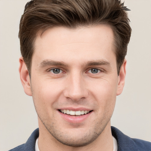 Joyful white young-adult male with short  brown hair and grey eyes