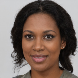 Joyful black young-adult female with long  brown hair and brown eyes