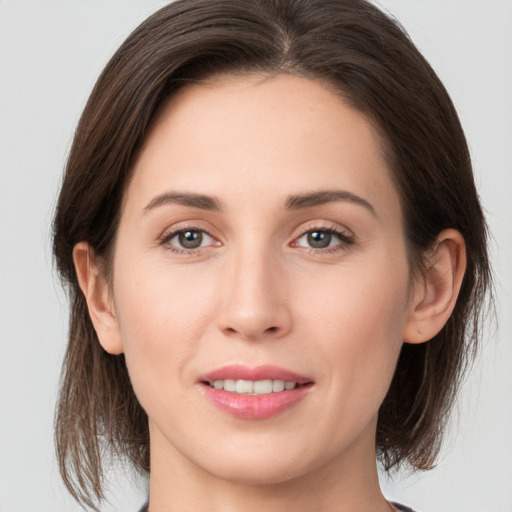 Joyful white young-adult female with medium  brown hair and grey eyes