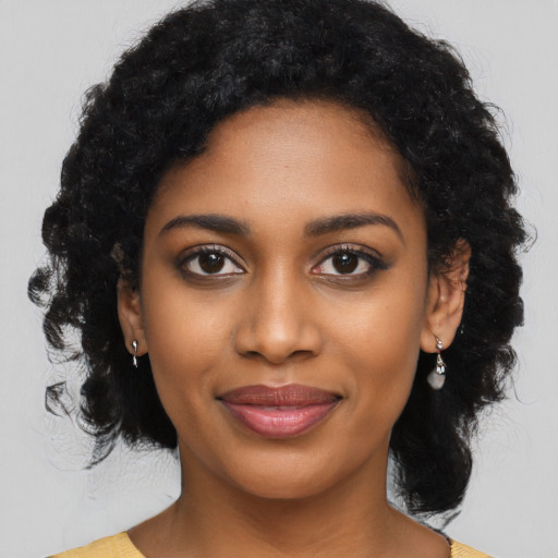 Joyful black young-adult female with long  black hair and brown eyes