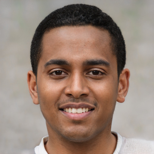Joyful black young-adult male with short  black hair and brown eyes