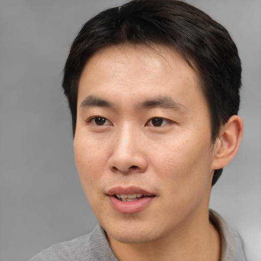 Joyful asian young-adult male with short  brown hair and brown eyes