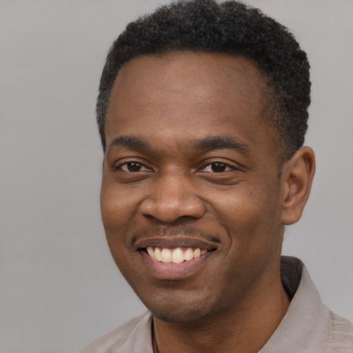Joyful black young-adult male with short  black hair and brown eyes