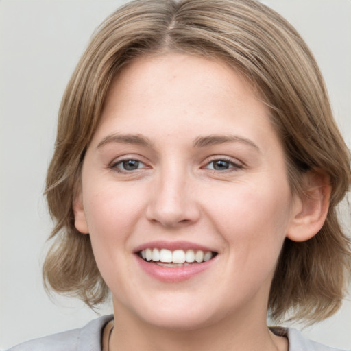 Joyful white young-adult female with medium  brown hair and blue eyes