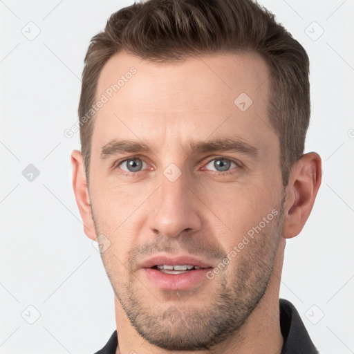 Joyful white young-adult male with short  brown hair and grey eyes